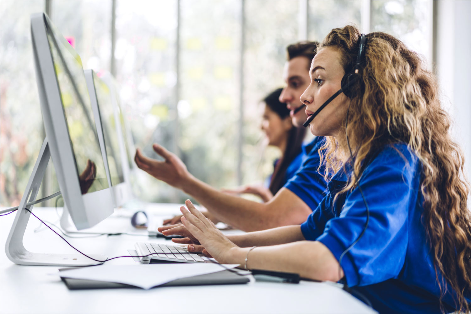 a team of call centre workers talking on the phone and using computers